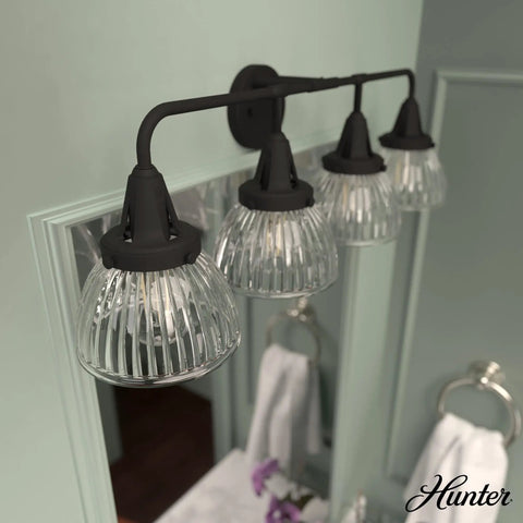 Cypress Grove 4 Light Natural Black Iron Vanity Light With Clear Holophane Glass Shade, mounted above a bathroom mirror.