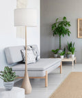 65 Inch Floor Lamp With Wood Toned Finish And White Cotton Shade Japandi Style E26 Base On Off Rotary Switch 5 Ft Cord Cozy Ambient Lighting Vibe For Living Room Or Bedroom set in a modern living room.