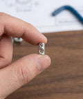 50 Pcs Premium M5 Cross Dowel Nuts Silver Carbon Steel Barrel Nut Connector Hardware held in hand for furniture assembly.