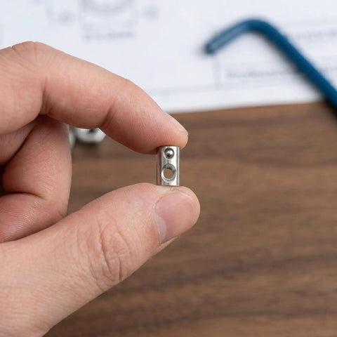 50 Pcs Premium M5 Cross Dowel Nuts Silver Carbon Steel Barrel Nut Connector Hardware held in hand for furniture assembly.
