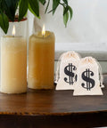 Beige Cotton Drawstring Gift Pouches With Money Sign For Cowboy Party Decor And Birthday Party Favors, next to candles