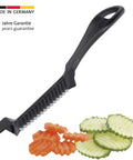 Westmark Crinkle Cutter Garnetta, black handle with ribbed blade; cucumber slices nearby