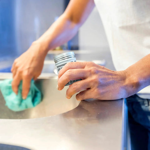 Person applying Micro Crystalline Wax Polish For Furniture, Wood, Leather And Metal That Delivers A Slick Shine, 65 ml, in kitchen.