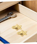 Retro Metal Duckbill Hasp Locks For Bags And Boxes With Secure Toggle Buckle Replacement Hardware For Easy Installation and Vintage Vibes On Your Travel Gear Or Storage Projects Today placed on a wooden drawer with a tool.