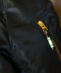 Embrite Glow Fob With Green Embrite Pellet, Aircraft-Grade Aluminum Keychain on black jacket zipper