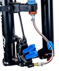 Close-up of BKM12 Hydraulic Brake Bleed Kit For Mineral Oil With Dual Syringes, bleed blocks, and hose attached to bike brake caliper