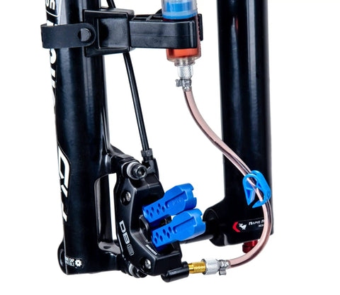 Close-up of BKM12 Hydraulic Brake Bleed Kit For Mineral Oil With Dual Syringes, bleed blocks, and hose attached to bike brake caliper