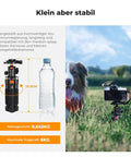 Aluminum compact desk tripod with ball head next to bottle, supporting DSLR, showing stability on grass with camera