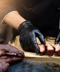 Chef using BBQ Glove Set With Four Cotton Liners And One Hundred Black Nitrile Gloves For Grillin And Food Prep to handle ribs