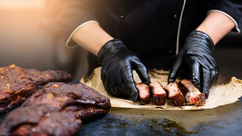 Chef using BBQ Glove Set With Four Cotton Liners And One Hundred Black Nitrile Gloves For Grillin And Food Prep to handle ribs