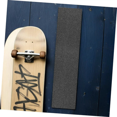 Two Pack Black Skateboard Grip Tape Sheets 33 Inch By 9 Inch Anti Skid Sandpaper next to a skateboard on a wooden surface