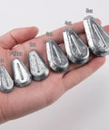Hand holding various weights of teardrop-shaped lead sinkers labeled 1 oz to 5 oz for freshwater and saltwater fishing