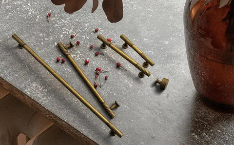 Hella Cool Vintage Antique Brass Cabinet Knobs With Classic Striped Groove and pulls on a table with decor.
