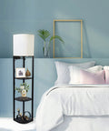 Smart RGB Shelf Floor Lamp With USB Ports And Power Outlet in bedroom next to bed, modern standing lamp in black with three shelves