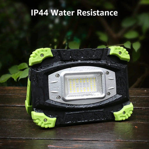 Portable LED Work Light 20W Rechargeable Flood Light With Built In Power Bank placed outdoors showcasing IP44 water resistance