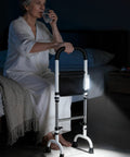 Senior woman using Quad Cane Standing Aid For Seniors, 5 Height Adjustable Grab Rail in bedroom at night