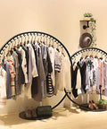 Freestanding clothing rack displaying assorted garments with a decorative design, showcasing an industrial style heavy duty coat rack for home and store.