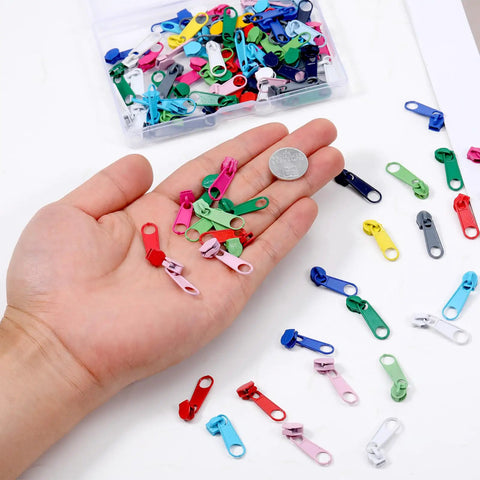 Hand holding colorful metal zipper sliders from 100 Pcs Metal Zipper Slider Replacement Kit Size 3 Universal Zipper Repair 12 Color Options