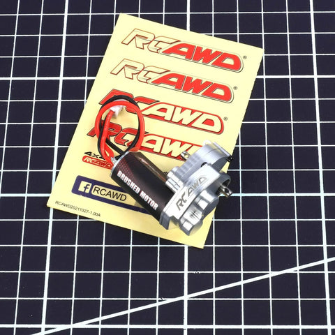 RCAWD brushed motor with red/black wires and aluminum gear case on yellow RC AWD card, front view