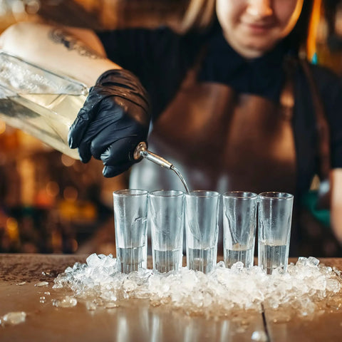 Bartender wearing black nitrile exam gloves, pouring liquid into tall glasses on ice, Black Nitrile Exam Gloves Medium 4 Mil Powder Free Latex Free Food Safe Medical Grade Puncture Resistant 100 Count Box Ideal For Medical And Food Handling And Laboratory Use Suitable For Medical Dental And Food Service Environments