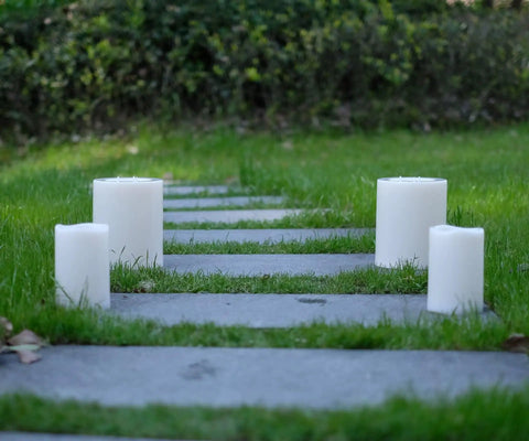 Four XL Flameless Pillar Candles with Remote on outdoor path, weatherproof LED, 6.45 by 8 inches, flickering warm light, waterproof resin build