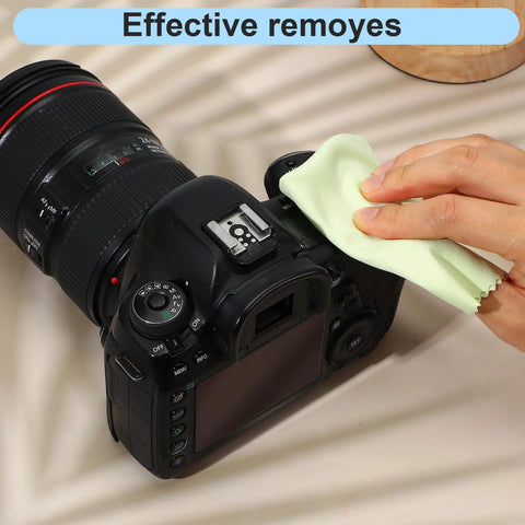 DSLR camera being wiped with a light green microfiber cleaning cloth.