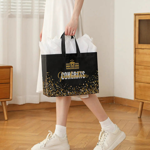 Person holding Two Pack 13 Inch Graduation Gift Bags With Tissue Paper And Cards, Reusable Nonwoven Gift Bags With Handles.