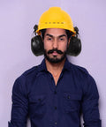 Heavy Duty Earmuffs Built Different Serving Killer Noise Reduction And Hard Hat Compatible Fit Locking Out Industrial Sound For Contractors And Shooters On Site Black Style With Thick Foam Pads worn with a yellow hard hat.