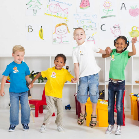 Children wearing Retro Groovy Floral Name Tag Stickers With Daisy Flower Nameplates in classroom, showcasing colorful designs.