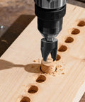 Top Notch Eight Piece Wood Plug Cutter Drill Bit Set Made From Tough Carbon Steel drilling a wood plug on a wooden surface.