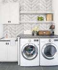 Laundry room with peel and stick wood wallpaper with herringbone pattern DIY friendly self adhesive removable grey and white vintage wall covering for walls and furniture renovation easy to apply repositionable no mess decor update behind shelves and appliances.
