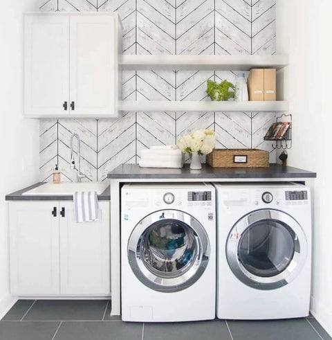 Laundry room with peel and stick wood wallpaper with herringbone pattern DIY friendly self adhesive removable grey and white vintage wall covering for walls and furniture renovation easy to apply repositionable no mess decor update behind shelves and appliances.