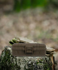 Tough As Nails Heavy Duty Plastic Toolbox With Interlocking Stackable Design And Thick Three Layer Foam Cushioning resting on a log.