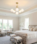 Six Light Frosted White Glass Globe Sputnik Chandelier in Modern Gold Finish hanging in a contemporary bedroom ceiling.