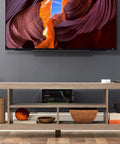 Living room setup with 12 Outlet Surge Protector Power Strip With 3420 Joules Of Surge Protection under TV in wooden stand.