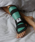 Large Left Foot Night Splint Built For Complete Achilles Rupture And Full Tendon Tear Recovery Keeps Your Foot Toes Down At One Hundred Fifty Five Degrees For Top Notch Healing And Chill Sleep Support, green and black on foot