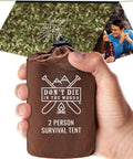 Hand holding 2-person survival tent in pouch with camo backdrop, "Don't Die In The Woods" text, featuring focus keyword: Survival Tent For Two Packable Emergency Shelter Made From Thick Mylar Space Blanket Reflective Heat Waterproof Camo Tube Tent Go To Backcountry Gear That Keeps You Warm In The Cold.