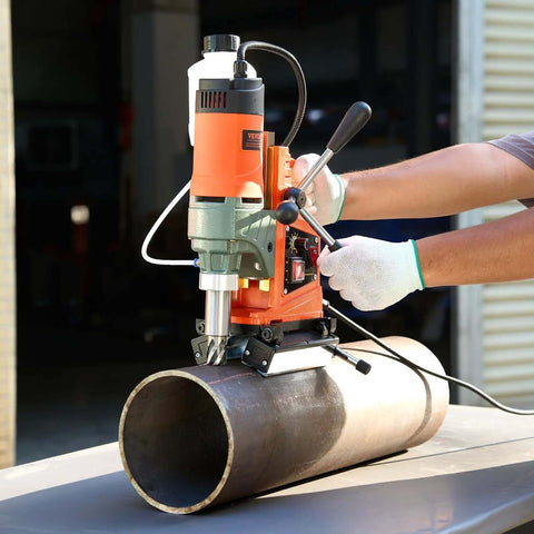 VEVOR magnetic drill press mounted on steel pipe; orange and gray unit in front view with clamp.