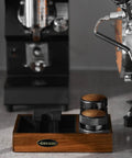 58mm Espresso Coffee Distributor Leveler with Stepless Height Adjustment on wooden base near espresso machine.
