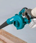 Compact Cordless Leaf Blower Delivering Hella Powerful 167 Mph Airflow And Variable Three Speed Control Built For Zero Hassle Yard Cleanup Ultra Lightweight Tool Only Package For Quick Pros showing teal blower in use with wood shavings.