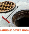Rock Solid T Shaped Manhole Cover Lifter Hook Forged From Reinforced Steel Rod With A No Slip Grip For Reaching Down Into Deep Sewers And Yanking Open Heavy Roller Doors next to a manhole.