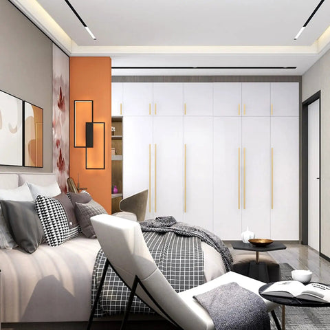 Modern bedroom with white cabinets featuring long, sleek brass handles, against a stylish bed setup.