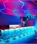 Bar area illuminated with 24 Pack Remote Hexagon RGB LED Panels Ceiling Lights With 358 Modes IP54 For Party And Gaming Easy Remote Control Color Changing Dimmable Lights To Create A Dope Home Theater Vibe Or Garage Setup installed on the ceiling.