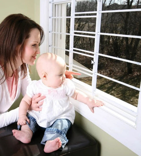 Mother and baby near window with Swing Open Style 6 Bar Window Guard For Child Safety White Finish Adjustable Width 24 To 42 Inches.