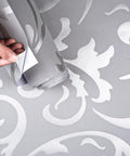 Silver Gray Peel And Stick Wallpaper 20.8 By 393 Inches Nonwoven 3D Floral Print Modern Wall Decor Removable And Renters Friendly Easy Install Durable Wrinkle Resistant For Quick Home Makeover being peeled by hand