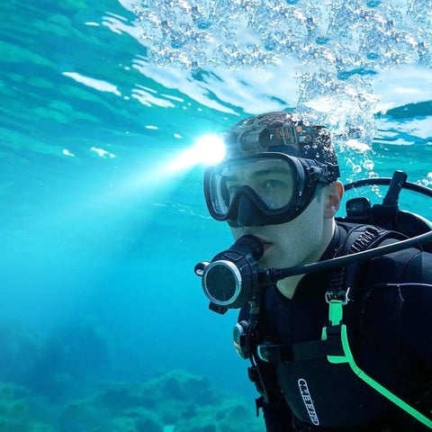 Diver using a Powerful 3000 Lumen Dive Headlamp with IP68 waterproof build underwater, flashlight illuminating the sea.