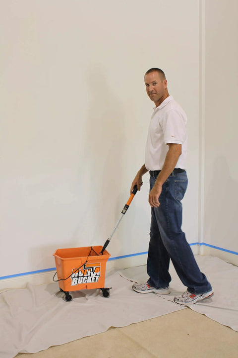 Man using RBC-323 Roll A Bucket with 3 inch caster wheels and brake, 6 gallon orange bucket for paint and tarps, sturdy design