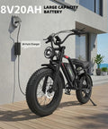 1500W Peak Electric Fat Tire Mountain Bike For Adults with 32 MPH Top Speed, shown charging outdoors