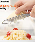 Person using Stainless Steel Handheld Cheese Grater With Soft Grip Handle And Zester over pasta, cheese shredding, kitchen tools.