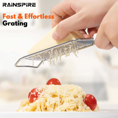 Person using Stainless Steel Handheld Cheese Grater With Soft Grip Handle And Zester over pasta, cheese shredding, kitchen tools.